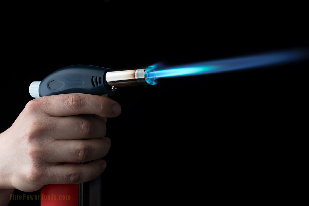 Butane torch with flame in hand
