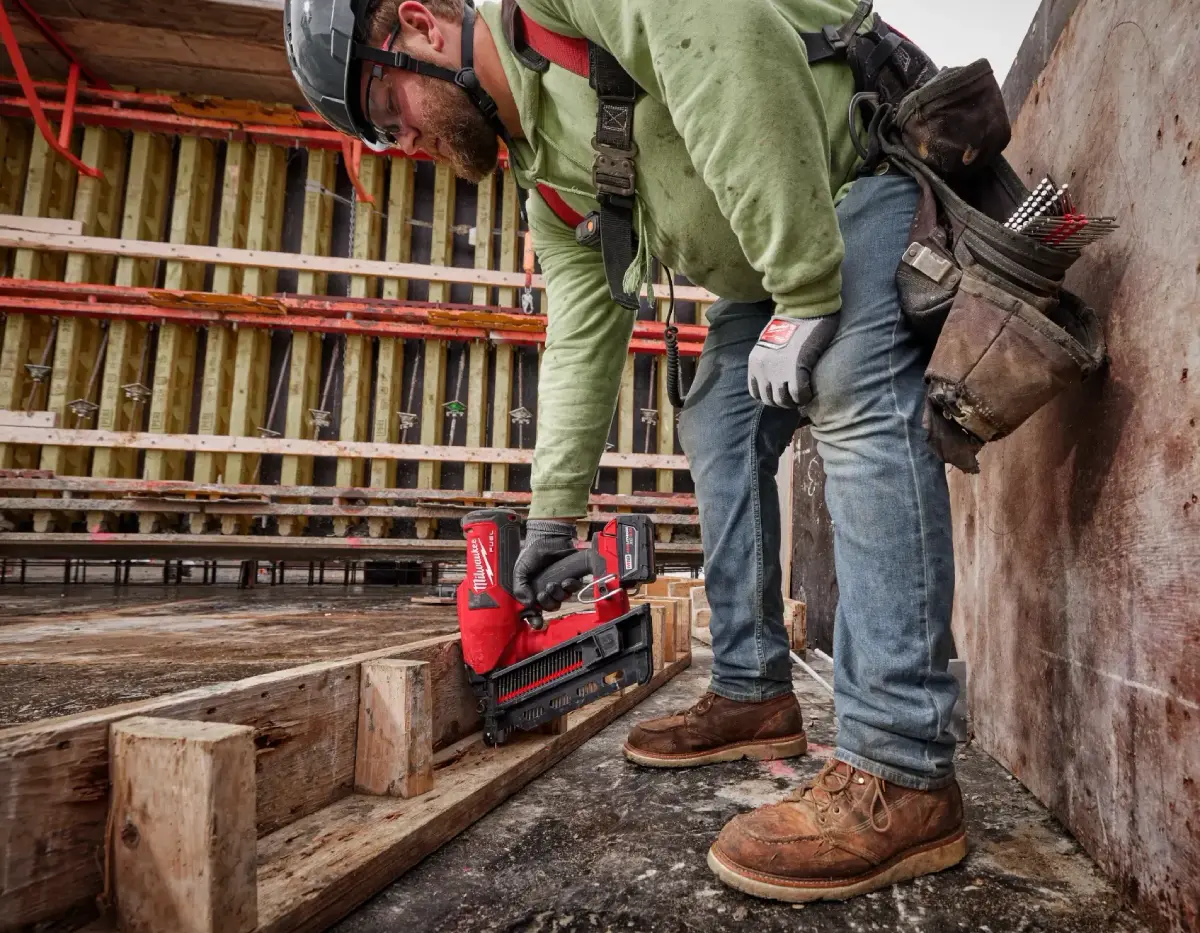 Construction worker using Milwaukee Duplex Nailer for concrete framework assembly.