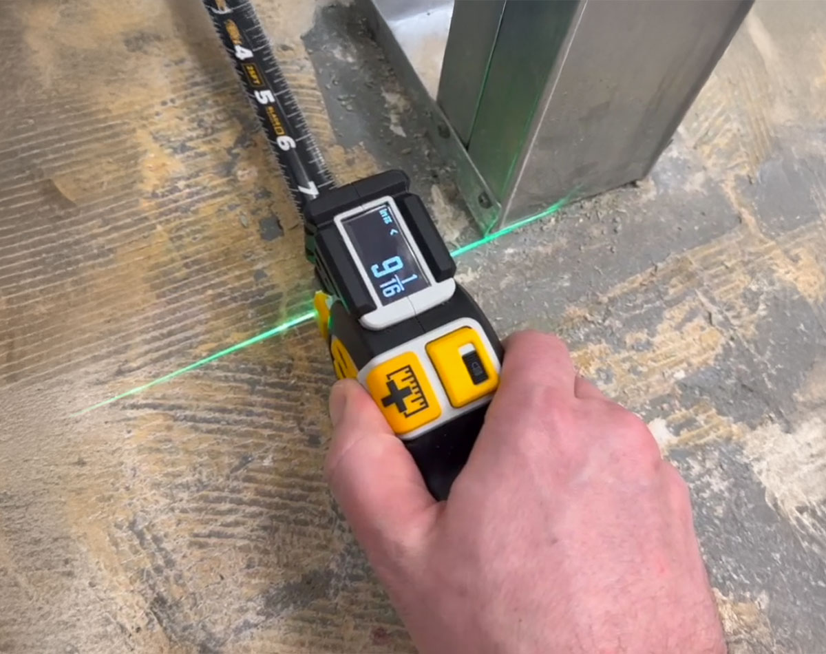 Man measuring the distance with a Digital Tape Measure